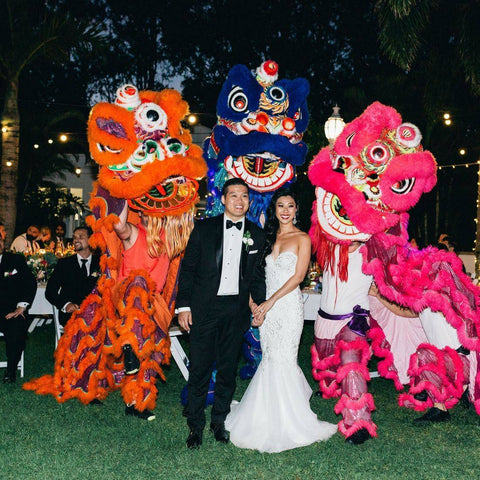 bride and groom in wedding attire in front of giant cultural dragons