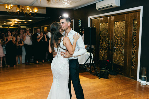 bride and groom kiss during first dance on dancefloor at their wedding