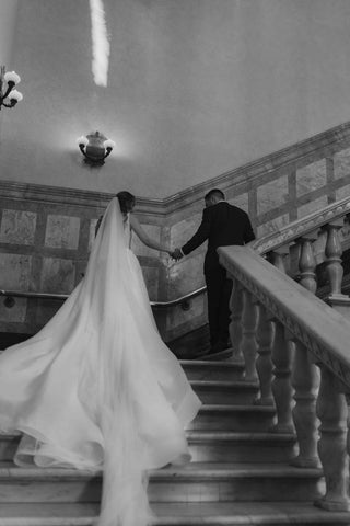 bride and groom walking up stairs in wedding attire