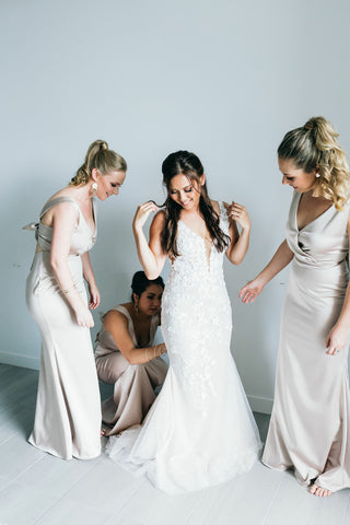  bride being helped into wedding gown by bridesmaids