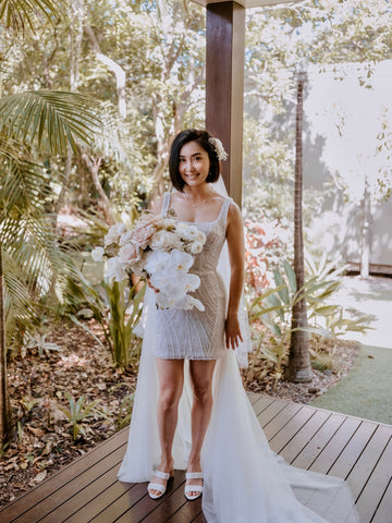 bride in beaded lace mini wedding dress with bouquet of flowers