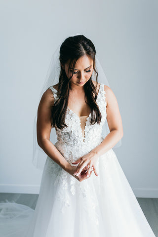 bride placing her engagement ring on her finger while wearing her wedding dress