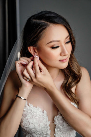 bride putting her earrings in her ear on morning of wedding