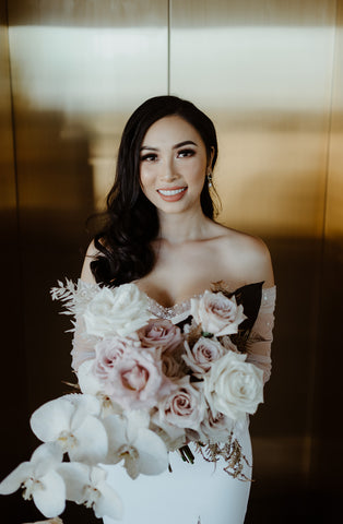 bride smiling while holding her bouquet of flowers after wedding ceremony