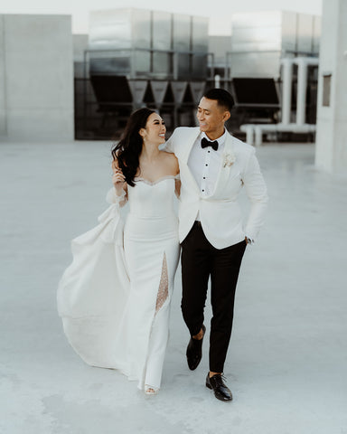 bride wearing custom wedding gown walking arm in arm with groom in his tuxedo