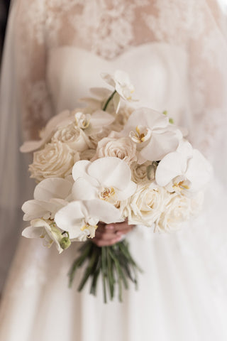 brides hands holding bouquet of flowers in front of her wedding dress