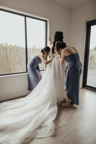 bridesmaids helping bride into her wedding gown