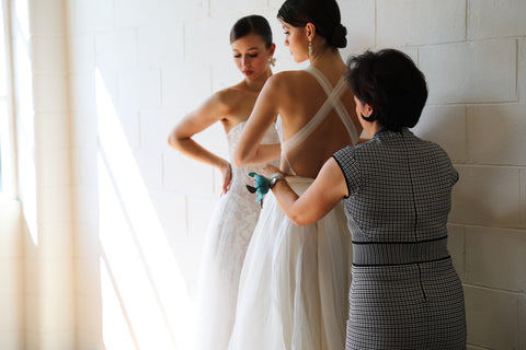fashion designer helping two models into wedding dresses
