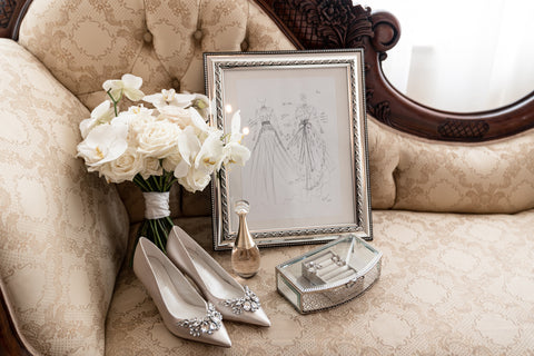 framed sketch of a wedding dress with heels bouquet and perfume on sofa