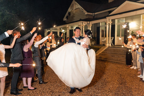 groom carrying his bride out of wedding reception in his arms