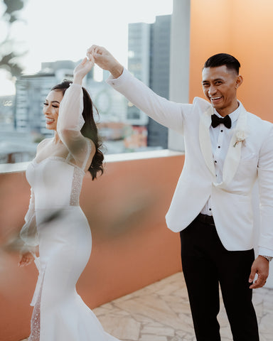 husband and wife in their custom wedding dress and suit dancing on rooftop