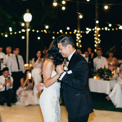 husband and wife on dance floor doing first dance in front of family and friends