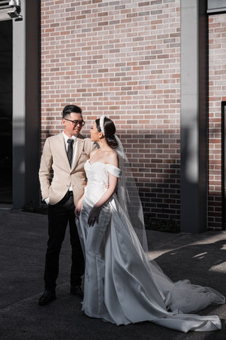 husband and wife on their wedding day posing in front of brick wall