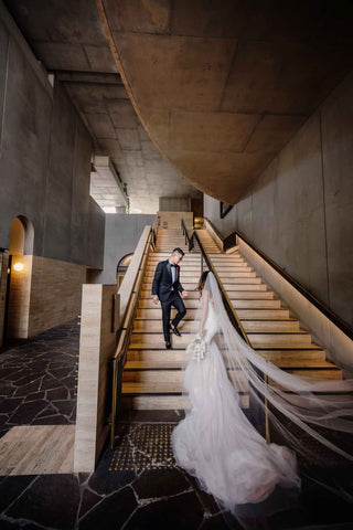 husband and wife walking up stairs in wedding day attire