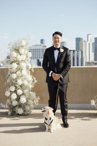 man wearing black suit at wedding with dog
