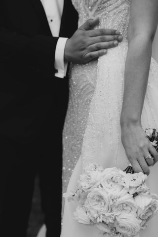 mans hand on brides hip as she holds bouquet of flowers