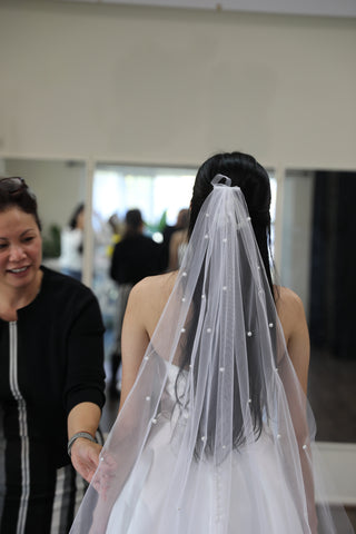 seamstress fitting wedding veil on womans head