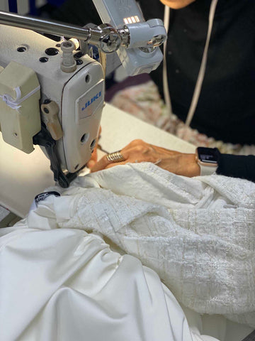 seamstress moving wedding dress under needle of sewing machine