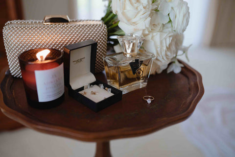 table top with lit candle ring box perfume and bouquet of flowers