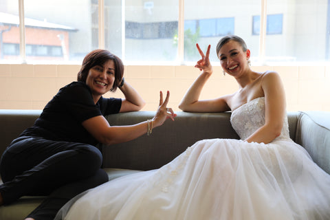 two women sitting on couch holding up peace signs