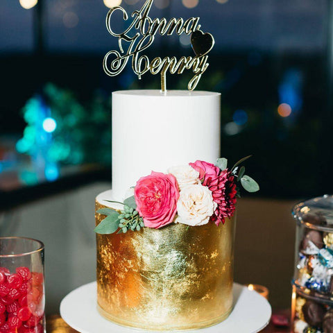 wedding cake with persons names on top and gold bottom with roses