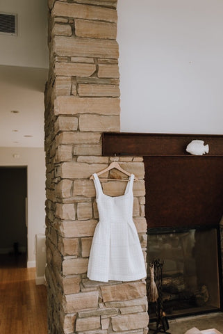 wedding gown hanging on brick wall beside fire place mantle