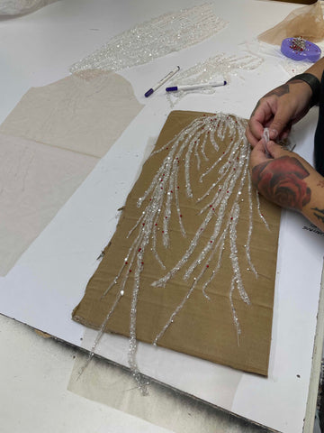 woman creating sleeves out of bridal lace on white table