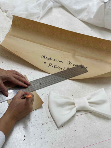 woman drawing next to pattern paper with fabric bow and ruler
