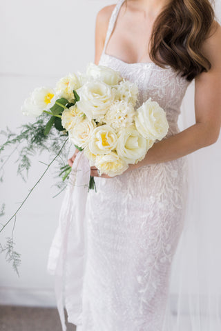 woman holding bouquet of flowers wearing custom wedding dress