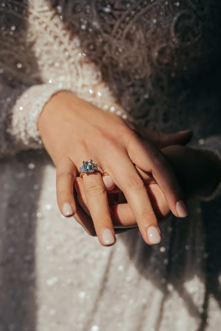 woman in lace wedding gown placing a ring on her own finger