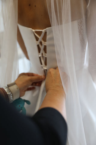 woman tying up back of corset wedding dress