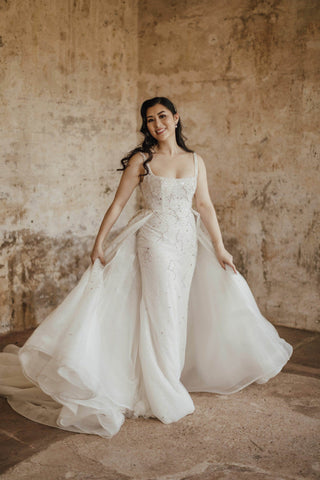 woman walking in wedding dress holding outer skirt