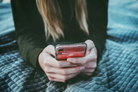 woman wearing black sweater holding red iPhone