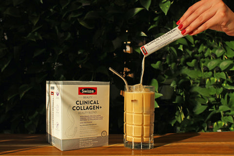 A box of Swisse Clinical Collagen+ Beauty Blends with a hand pouring the Chai Latte powder satchel into a glass of milk