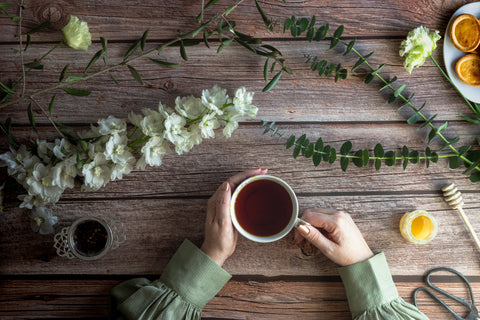 Cup of tea in woman's hands on wooden table