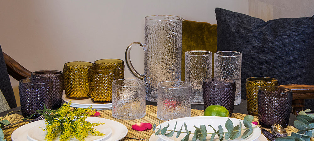 vaso de cristal de diferentes tamaños y colores sobre mesa circular elegante y escenario natural