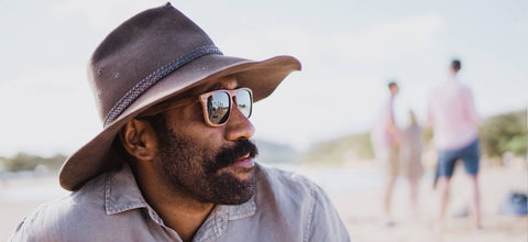 a man with sunnies and a hat at the beach