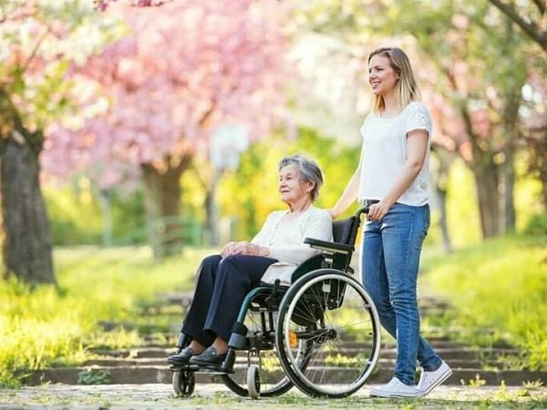 girl pushing an elderly woman in a wheelchair