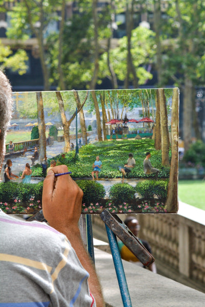 A man painting a canvas outside