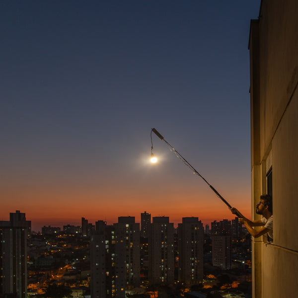 A night photo of an outstretched pole with a lit lamp