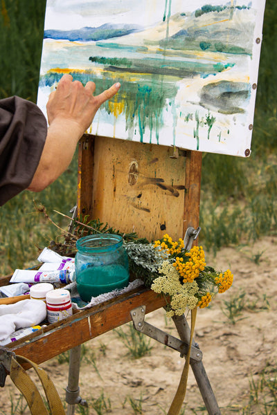A painter drawing on canvas in countryside