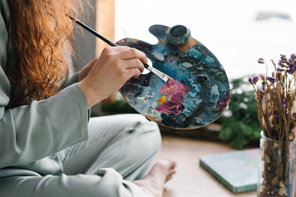 A painter holding a brush and color palette