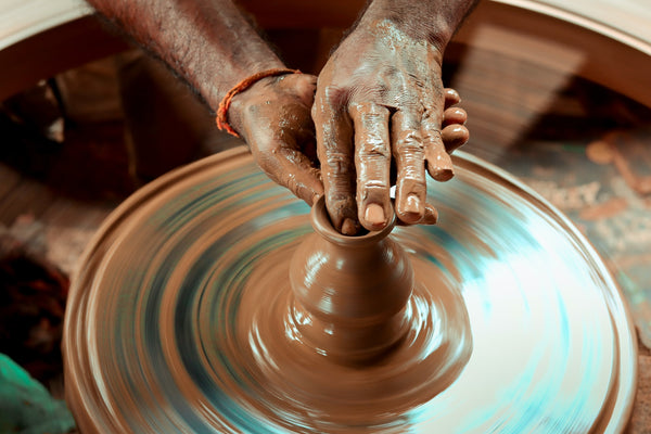 A person making a vase on a potter wheel