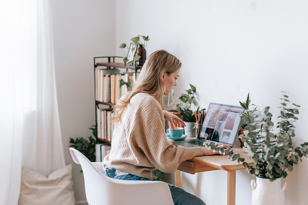 A photo of a freelancer working on a laptop with photos on screen at home