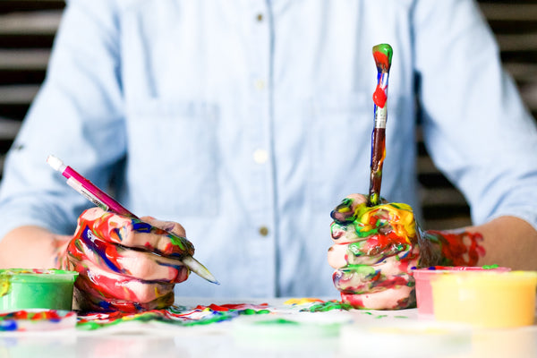 A photo of a person in blue shirt holding a click pen and a paintbrush