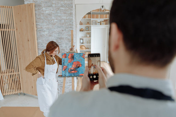 A photo of a woman in brown long sleeves standing beside the painting