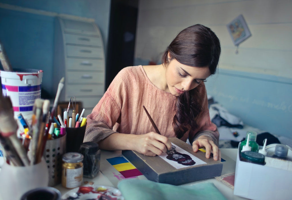 Ein Bild von einer Frau in einer braunen Bluse, die malt