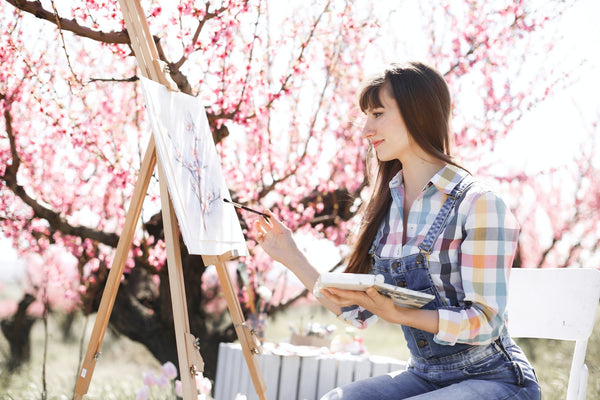 A photo of a woman sitting on a bench infront of a painting photo