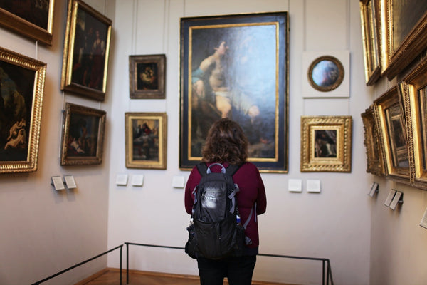 A photo of a woman standing in front of paintings