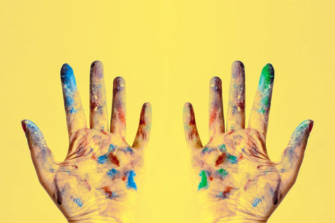 A photo of both hands stained with paints
